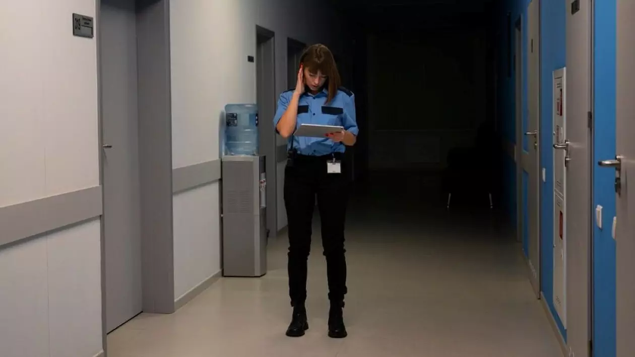 O femeie aflată la locul de muncă, în uniformă, verifică registrul în timp ce-și ține mâna la tâmplă
