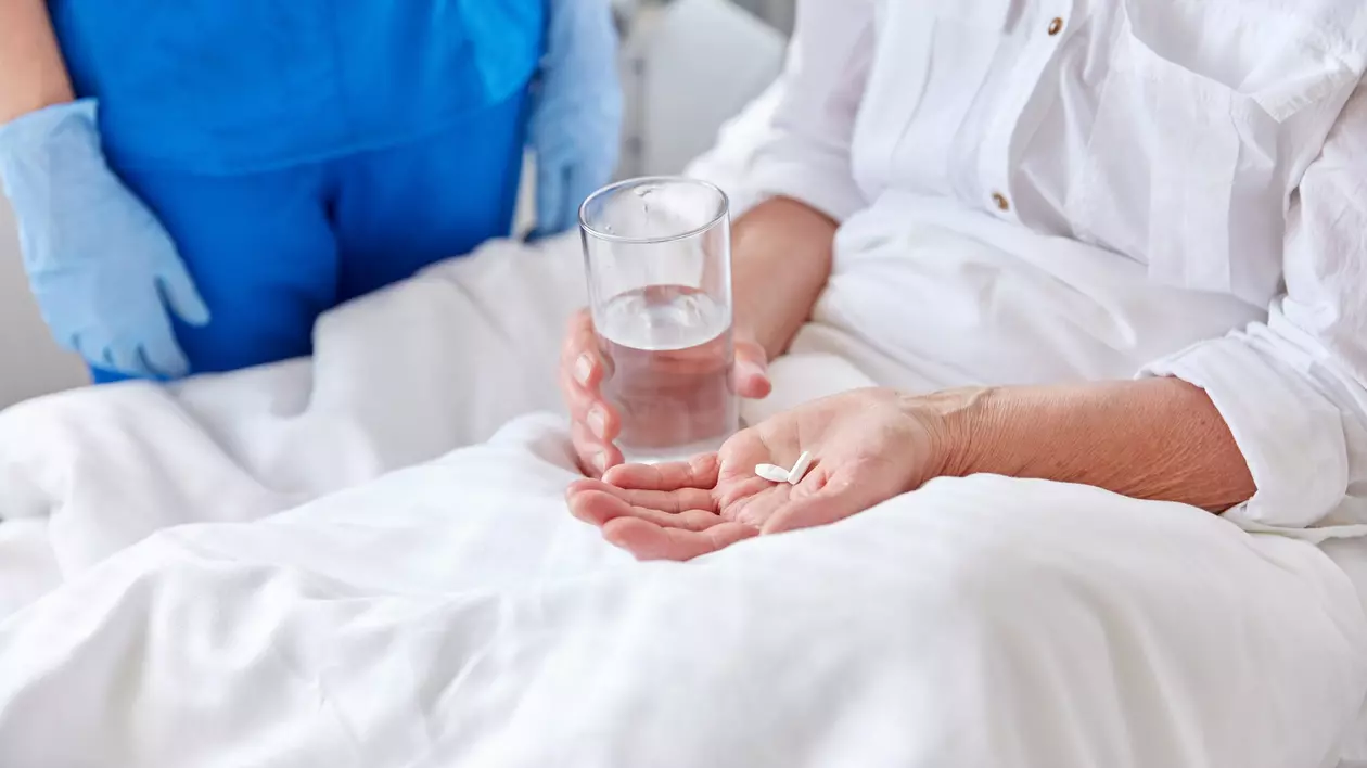 femeie pe patul de spital ia medicamente. Foto: Shutterstock