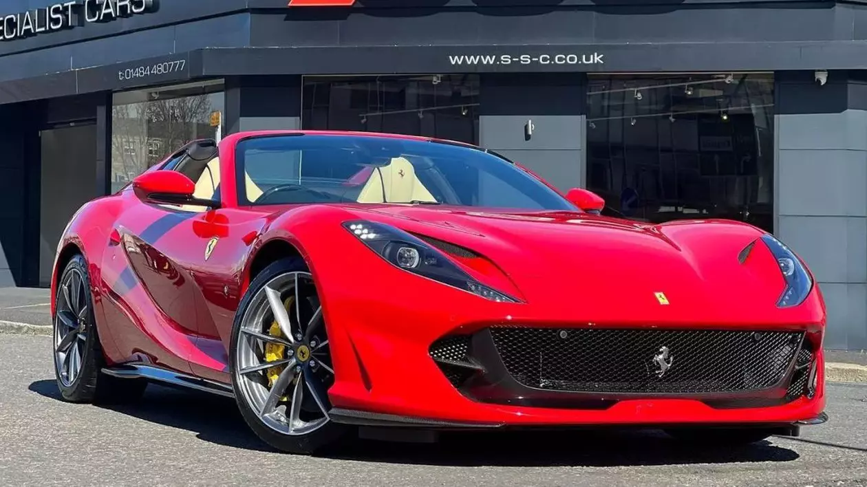 O mașină roșie Ferrari 812 GTS Spider F1 de lux stă parcată pe o stradă, în fața unui magazin