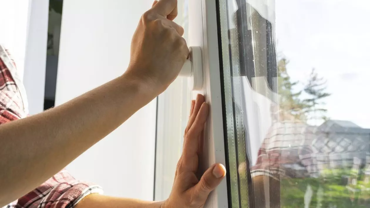 Mâna ține mânerul unei ferestre cu geam dublu din plastic, închiderea și deschiderea ferestrei cu un mecanism rotativ, poziția mânerului pentru ventilație, micro-ventilație