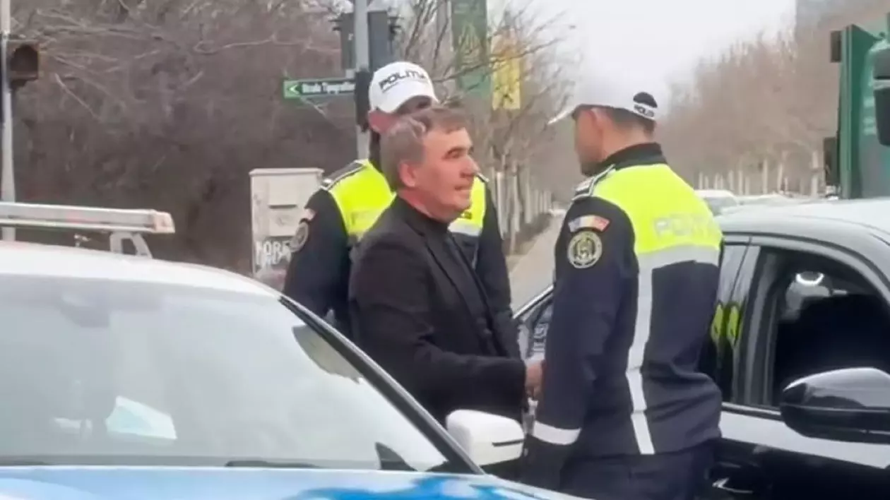 Gică Hagi dă mâna cu unul dintre agenți după ce a fost oprit în trafic. Fostul mare fotbalist este îmbrăcat elegant, în negru