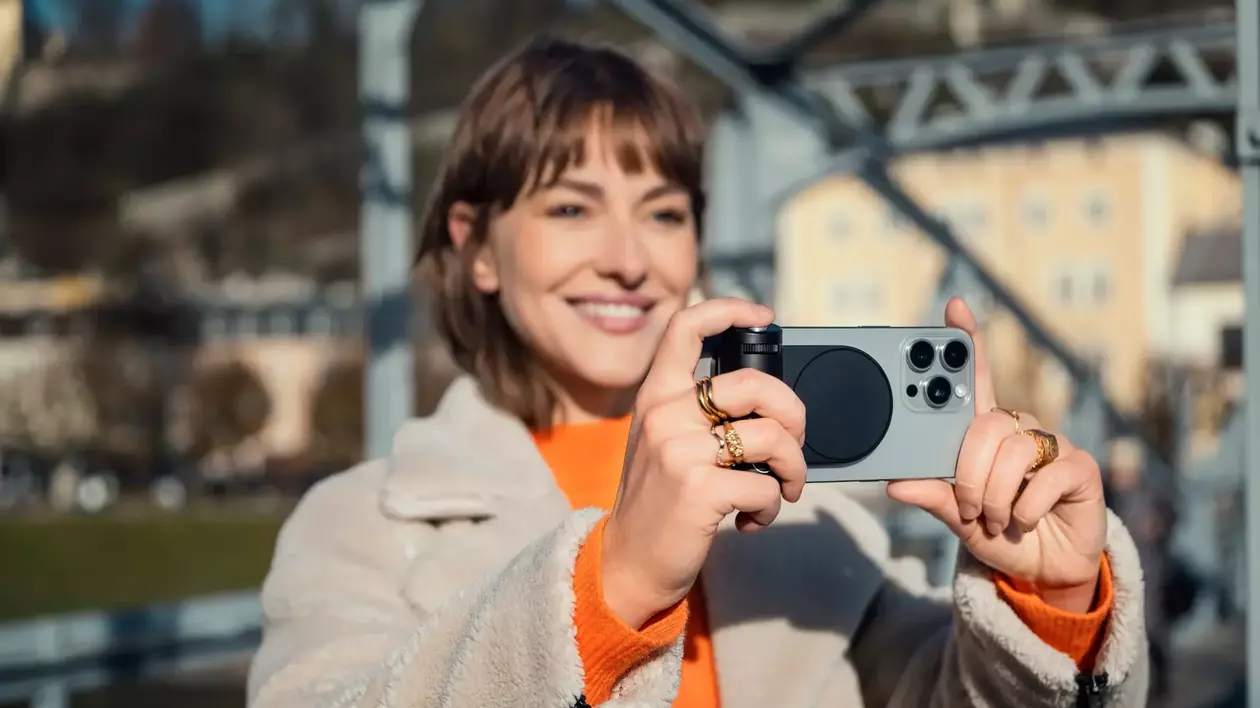 Persoană făcând o poză cu un iPhone la care este atașat suportul Leica Lux.