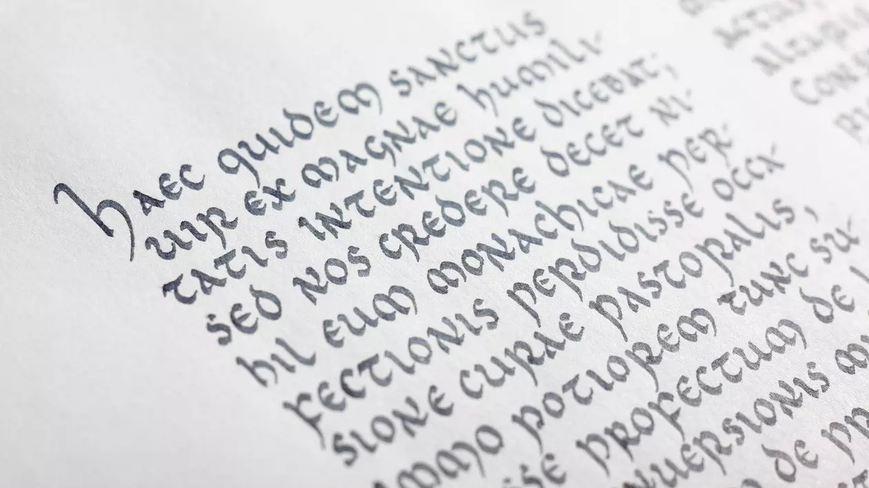 un text în limba latină pe o foaie albă Vedere de aproape a scrierii antice. Scriere uncială medievală. Limba latină.