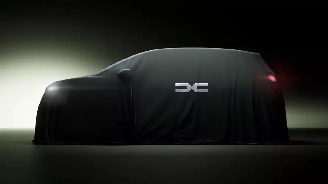 Un teaser care reprezintă o nouă mașină electrică Dacia, sub o husă gri cu logo-ul brand-ului desenat pe ea.