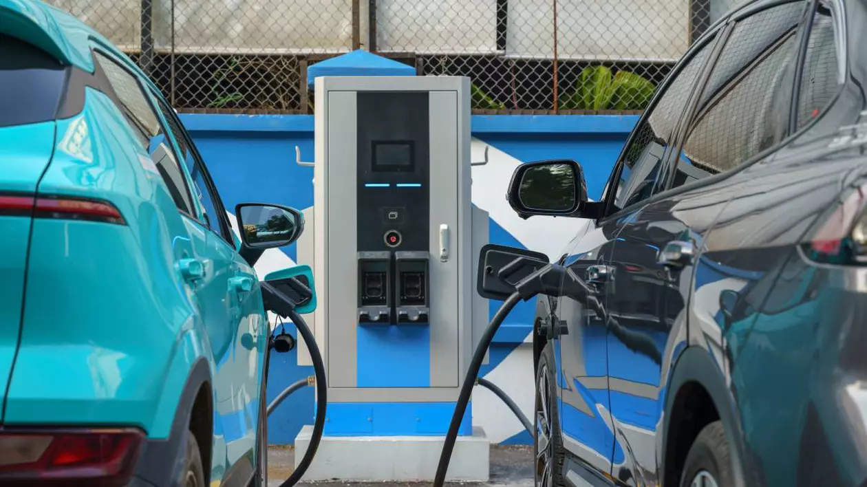 doua masini electrice culoare albatra in fata unei statii de reincarcare