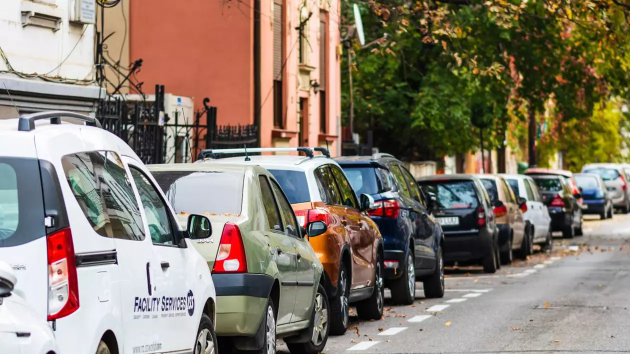 masini parcate pe o strada din bucuresti. in partea stanga este o casa portocalie
