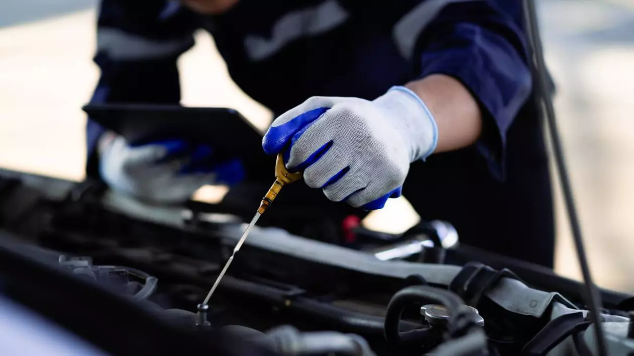 mecanic auto care verifica nivelul de ulei al motorului masinii cu ajutorul unei joje