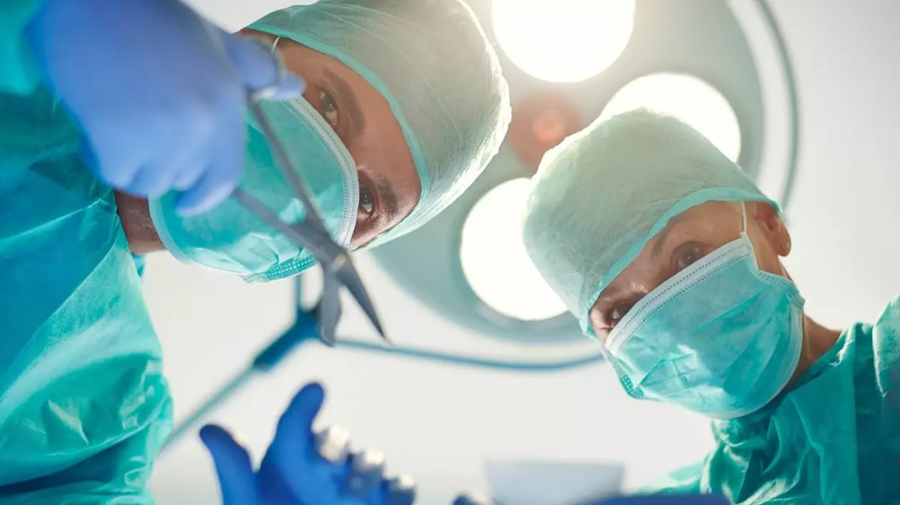 Doi medici chirugi pregătiți de o intervenție. Ambii sunt echipați corespunzător