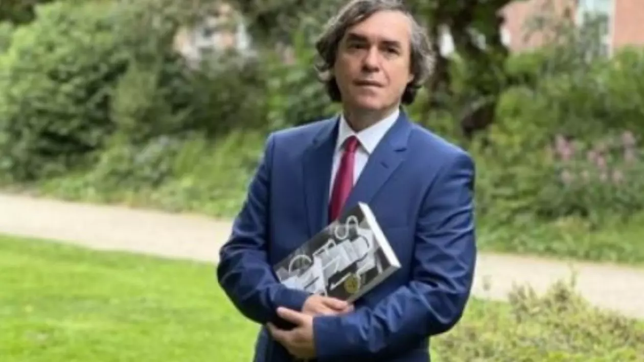 Scriitorul român Mircea Cărtărescu , aflat în aer liber și înconjurat de natură, ține în brațe romanul său, Solenoid,