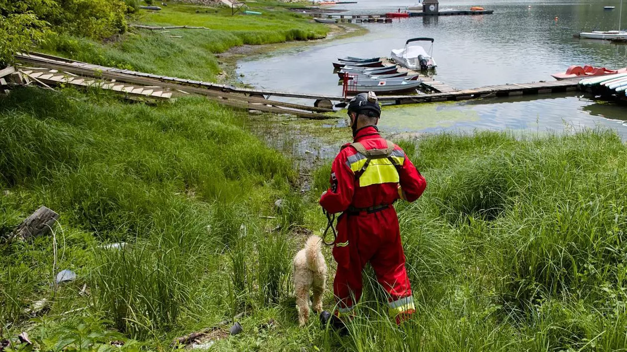 Un pompier împreună cu un câine dresat special caută o persoană dispărută lângă un lac