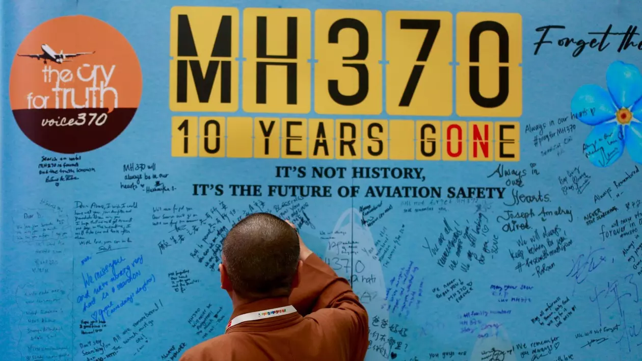 Om care scrie un mesaj pe un panou realizat cu ocazia Zilei de comemorare a zborului MH370- 3 martie 2024.