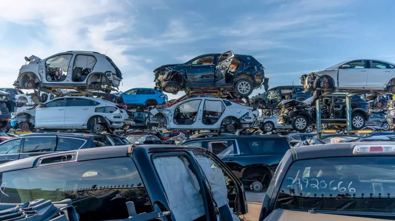 Un parc auto de mașini vechi, în care autoturismele, unele dezmembrate, sunt așezate unele peste altele