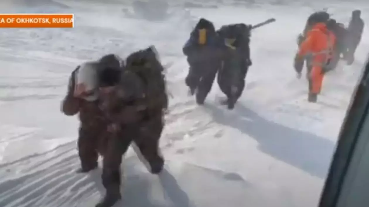 Pescarii ruși blocați pe bancul de gheață în Marea Ohotsk sunt transportați cu greu la elicopter de salvatori. Afară este foarte frig și vântul bate puternic