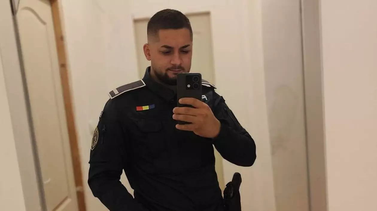 Un bărbat îmbrăcat în uniformă de polițist, cu ceas la mână, își face un selfie cu telefonul în oglinda unei camere