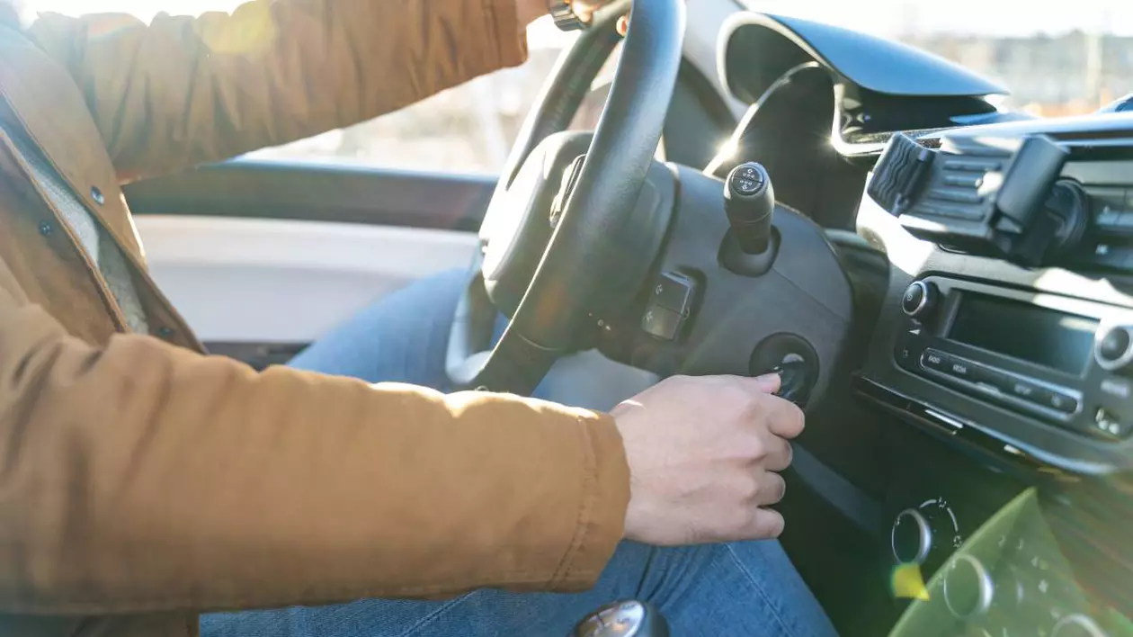 barbat aflat la volanul unei masini in timp ce porneste motorul cu cheia