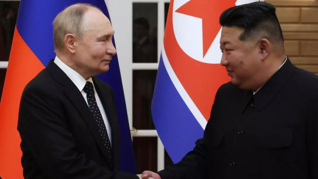 Președintele rus Vladimir Putin și liderul nord-coreean Kim Jong își strâng mâinile. Ambii sunt cu zâmbetul pe buze și îmbrăcați la patru ace