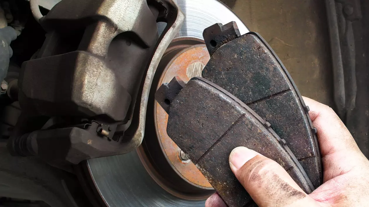 placute de frana auto prezentate de un mecanic, pe fundal disc de frana