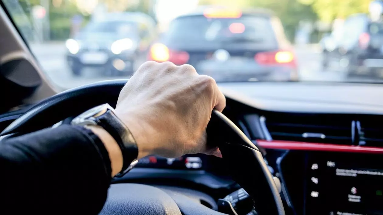Un bărbat care poartă ceas ține mâna pe volanul unei mașini, în timp ce se află în trafic. Șoferii din România și Bulgaria, cei mai periculoși
