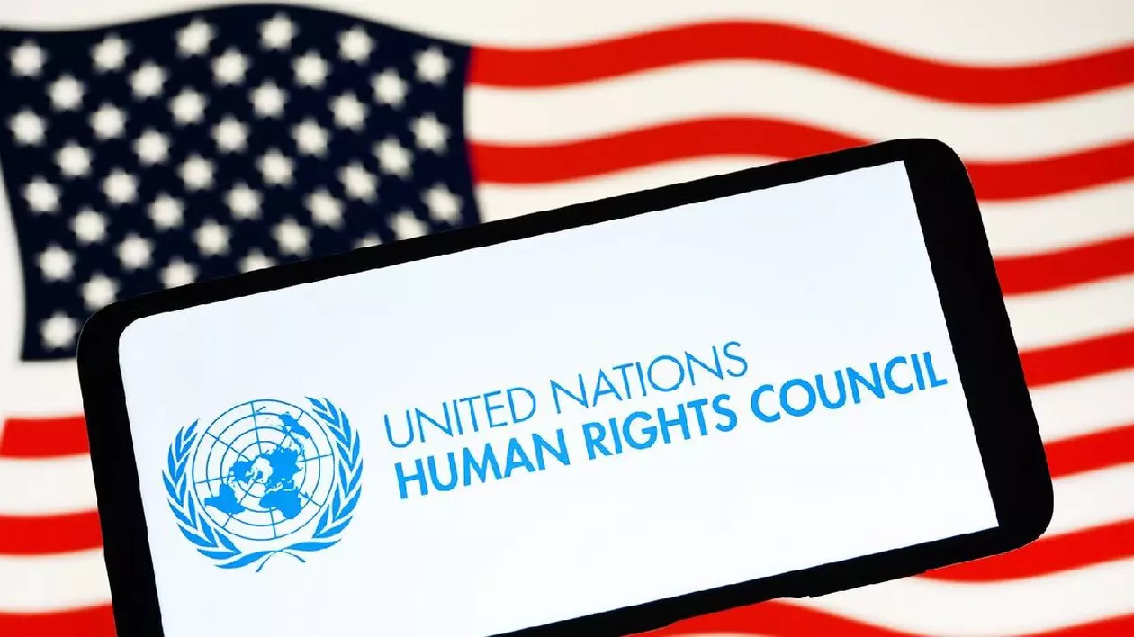 Logo-ul Consiliului Organizației Națiunilor Unite pentru Drepturile Omului (UNHRC) este văzut pe un smartphone și steagul SUA în fundal.