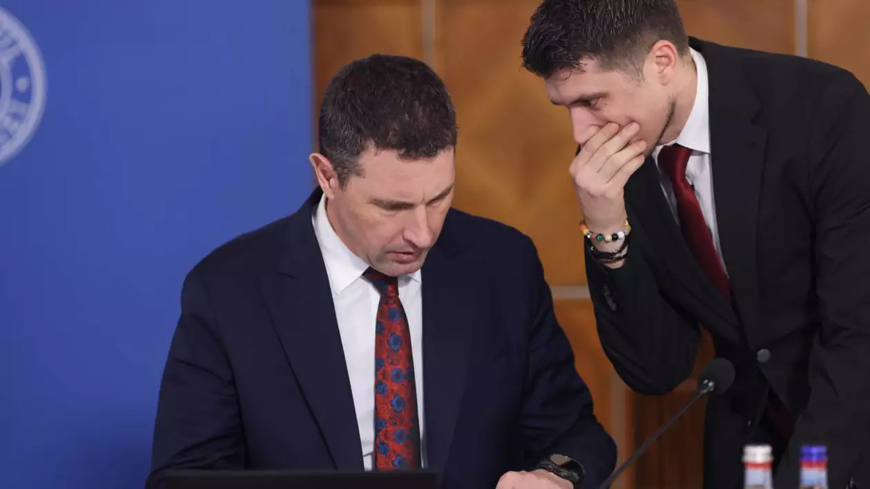 ministrul de finante, Tanczos Barna in timpul unei sedinte de guvern, langa el este un coleg care ii sopteste ceva la ureche