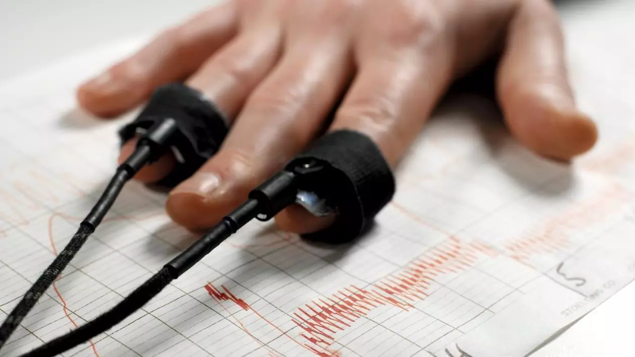 Testul detectorului de minciuni. Contoare de puls pe degetele unui bărbat utilizate pentru un test de detector de minciuni sau poligraf. Sub mâinile subiectului se află urmele produse de poligraf. Sursă foto: Profimedia