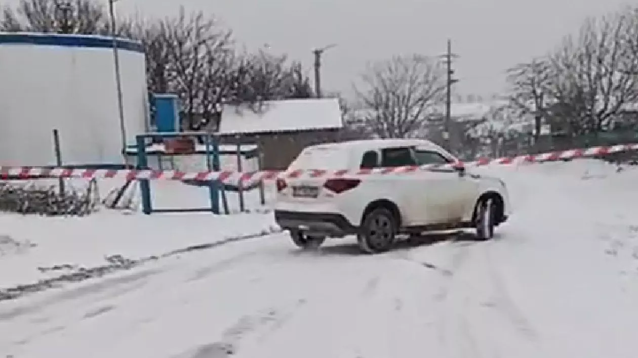 strada inchisă intr-o comună din constanta, acoperita de zapada, masina alba in fundal