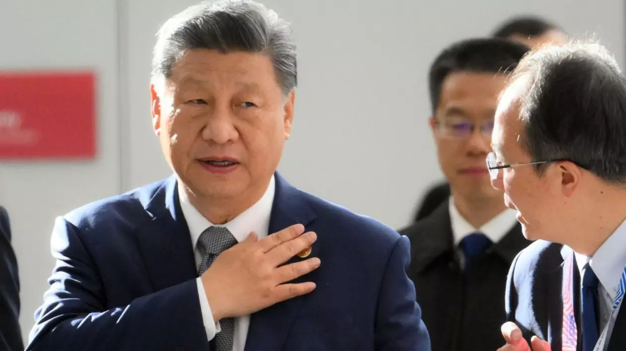 Președintele chinez Xi Jinping sosește la sesiunea Outreach/BRICS Plus, alături de unul dintre colaboratori. Este îmbrăcat la costum și afișează o mină serioasă