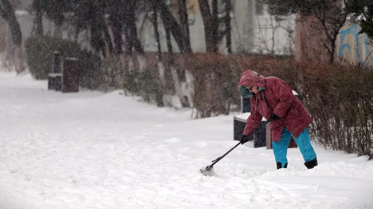 Femeie surprinsă în timp ce dă zăpada.