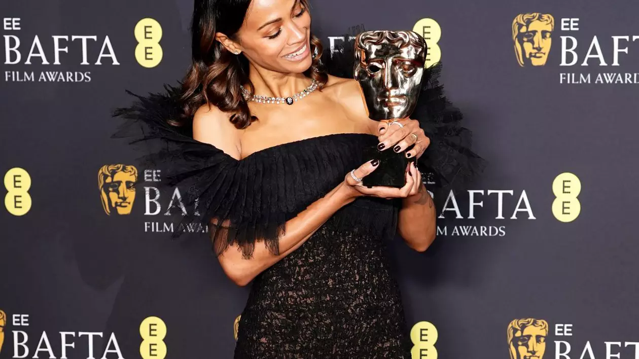 Zoe Saldana ține în mână Premiul BAFTA primit pentru cea mai bună actriță în rol secundar.