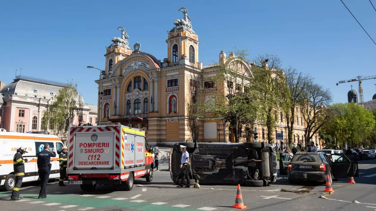 fotografie de la un accident rutier din cluj in care o masina s-a rasturnat. in partea din stanga sunt masinile ambulantei si a pompierilor, se observa cativa politisti langa masina rasturnata