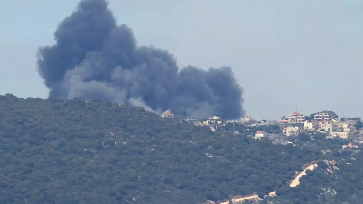 imagine cu un oras micut peste un deal de padure, se observa fum negru in urma unui atac