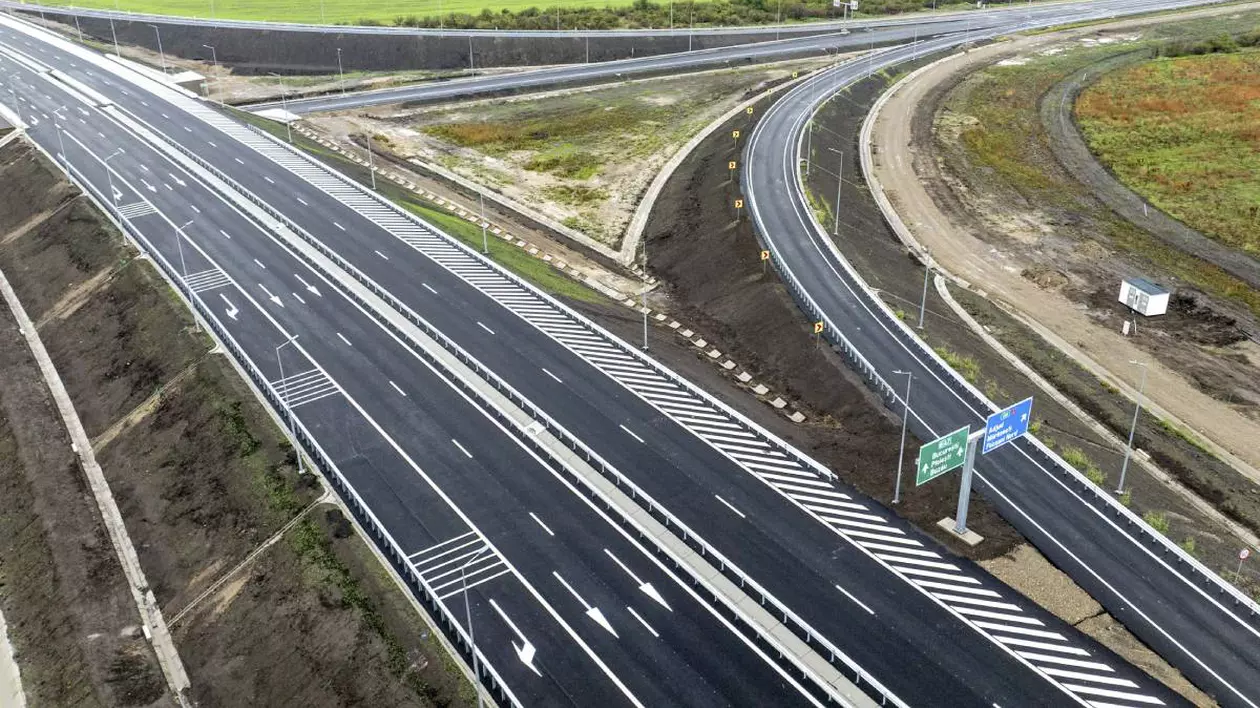 autostradă nou construită cu mai multe benzi pe fiecare sens de circulație și marcaje rutiere. nod rutier cu bretele de acces și ieșire. indicatoare rutiere pentru direcțiile de mers și parapete de siguranță