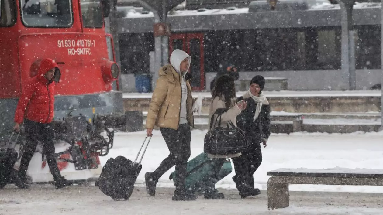 Mai mulți oameni cară bagaje în Gara de Nord din București și se vede locomotiva roșie a unui tren, într-o zi în care ninge și pe jos este zăpadă