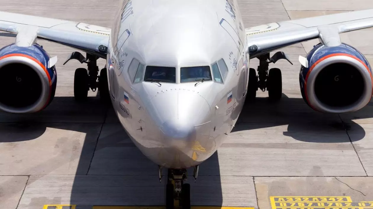 Un avion Boeing de culoare argintie rulând pe o pistă a unui aeroport