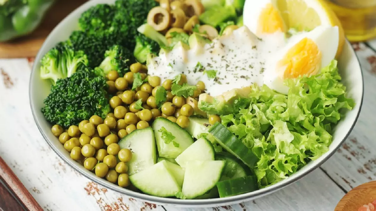 Cum să te adaptezi la ora de vară 2025. Ce alimente să consumi și ce să eviți - Imagine cu un bol cu salată, în care se disting mazăre, măsline, brocoli, salată verde, lămâie, ou şi un sos alb.