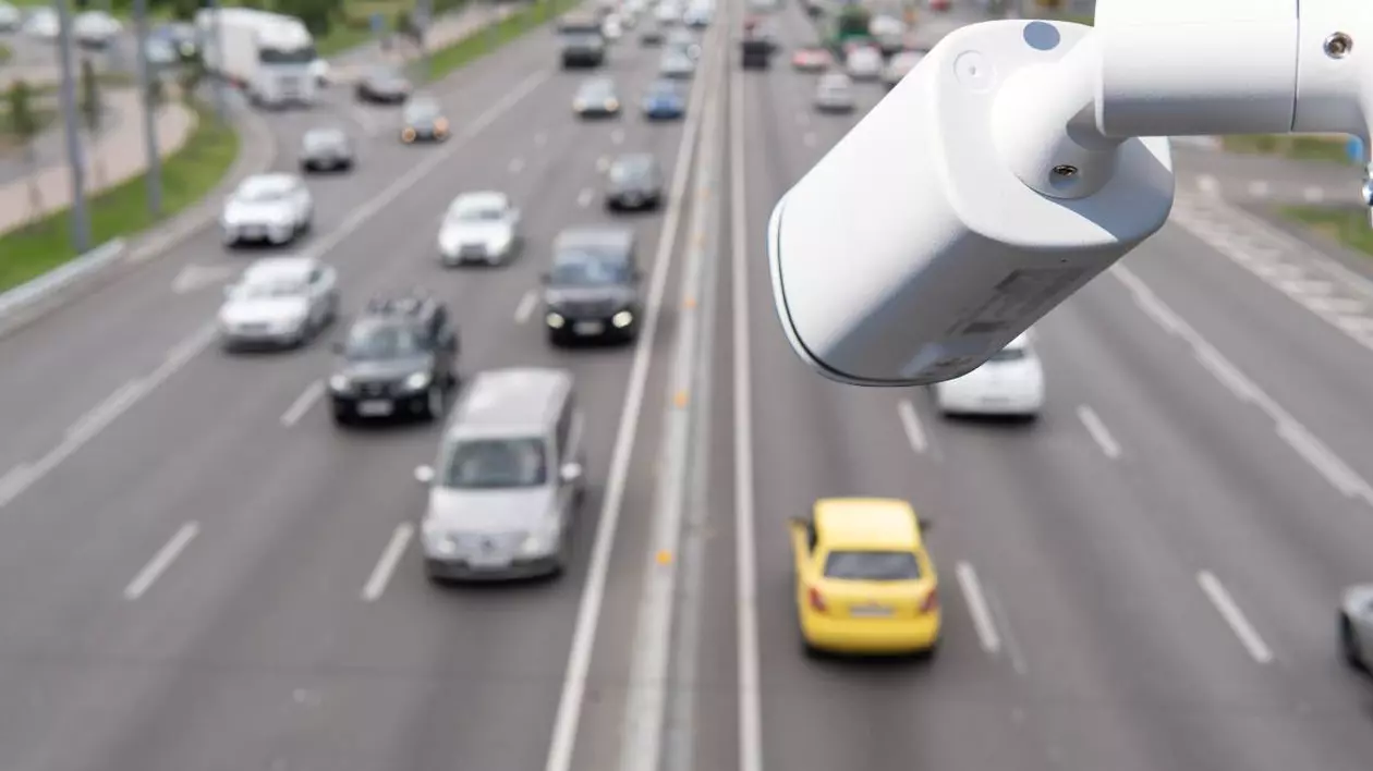 camera de filmat alba pentru monitorizarea traficului, pe fundal sunt mai multe masini care circula pe dublu sens