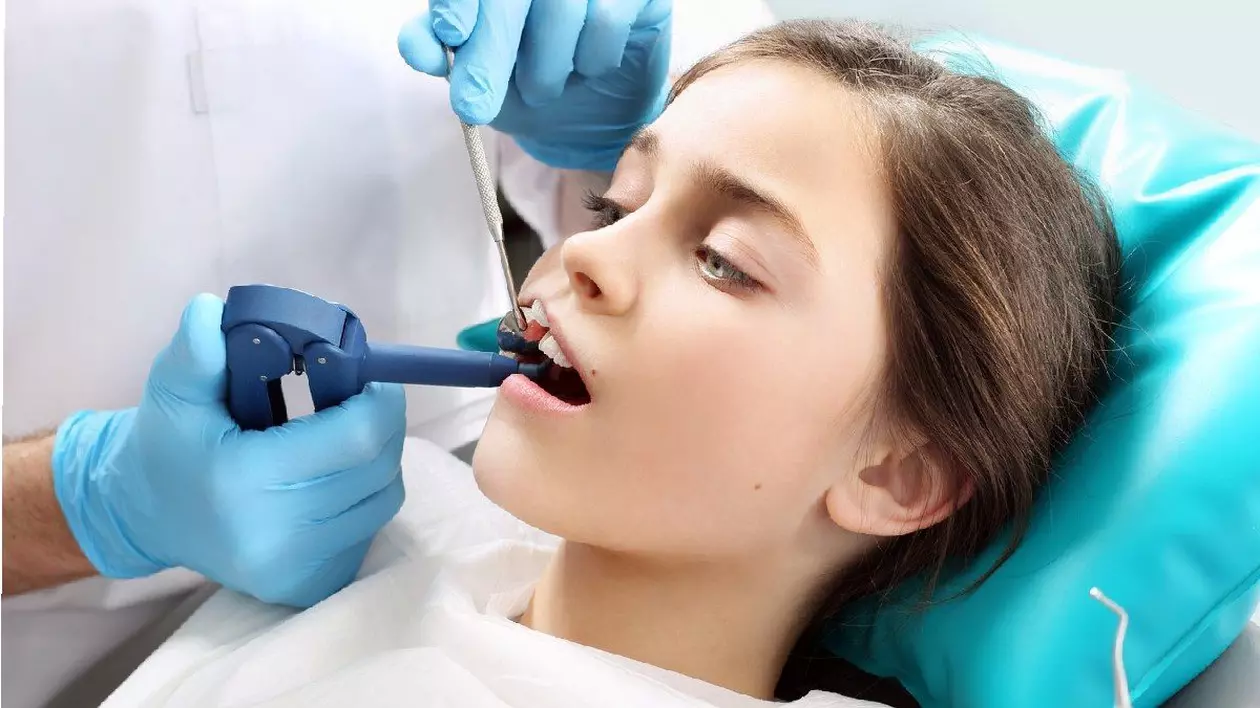 un copil pe un scaun dentar în timpul unui tratament dentar. tratamentul pierderii dinților, un copil la dentist. cariile dentare la copii, principii de igienă orală. sigilarea dinților, un copil la dentist. un cabinet dentar, un copil pe un scaun dentar. sigilare cu lumină, un copil într-un cabinet dentar
