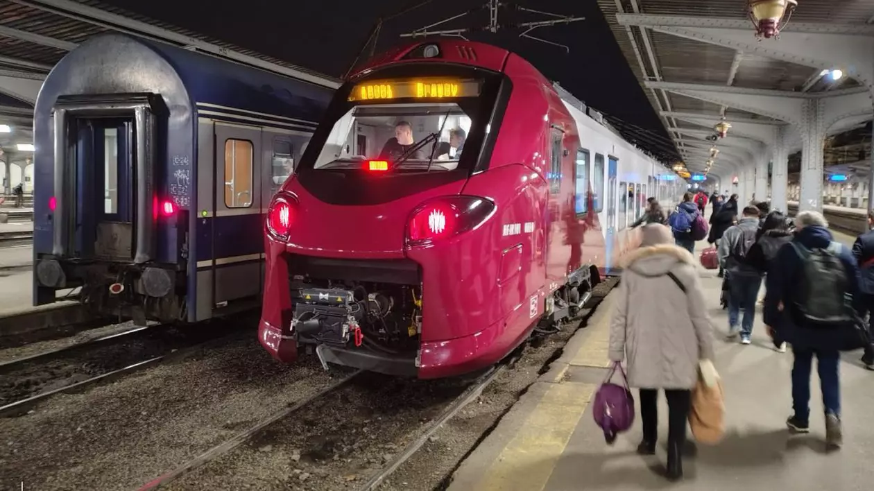 Tren al CFR Călători, de culoare roșie, în gara CFR din București, în timp ce mai mulți oameni se află pe peron
