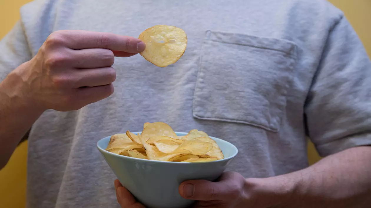 un bărbat care mănâncă chipsuri