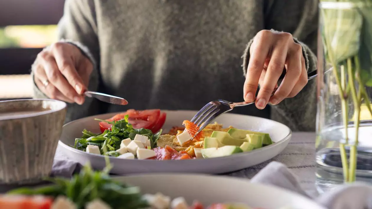 persoana care mananca dintr-un bol plin cu salata de legume