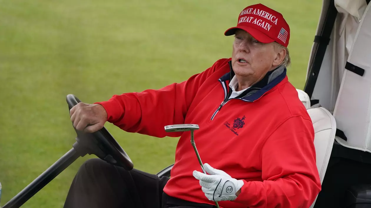 Donald Trump surprins într-o ținută sport, cu o șapcă roșie pe cap pe care scrie „Make America Great Again”