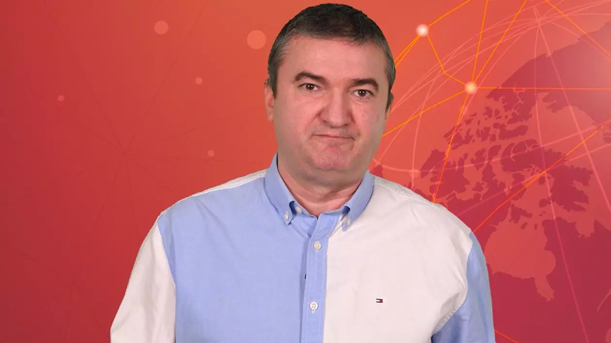 Dorin Chioțea, redactor-șef Libertatea, îmbrăcat cu o cămașă de culoare alb-bleu, pe fundal roșu, în studioul 5 știri by Libertatea