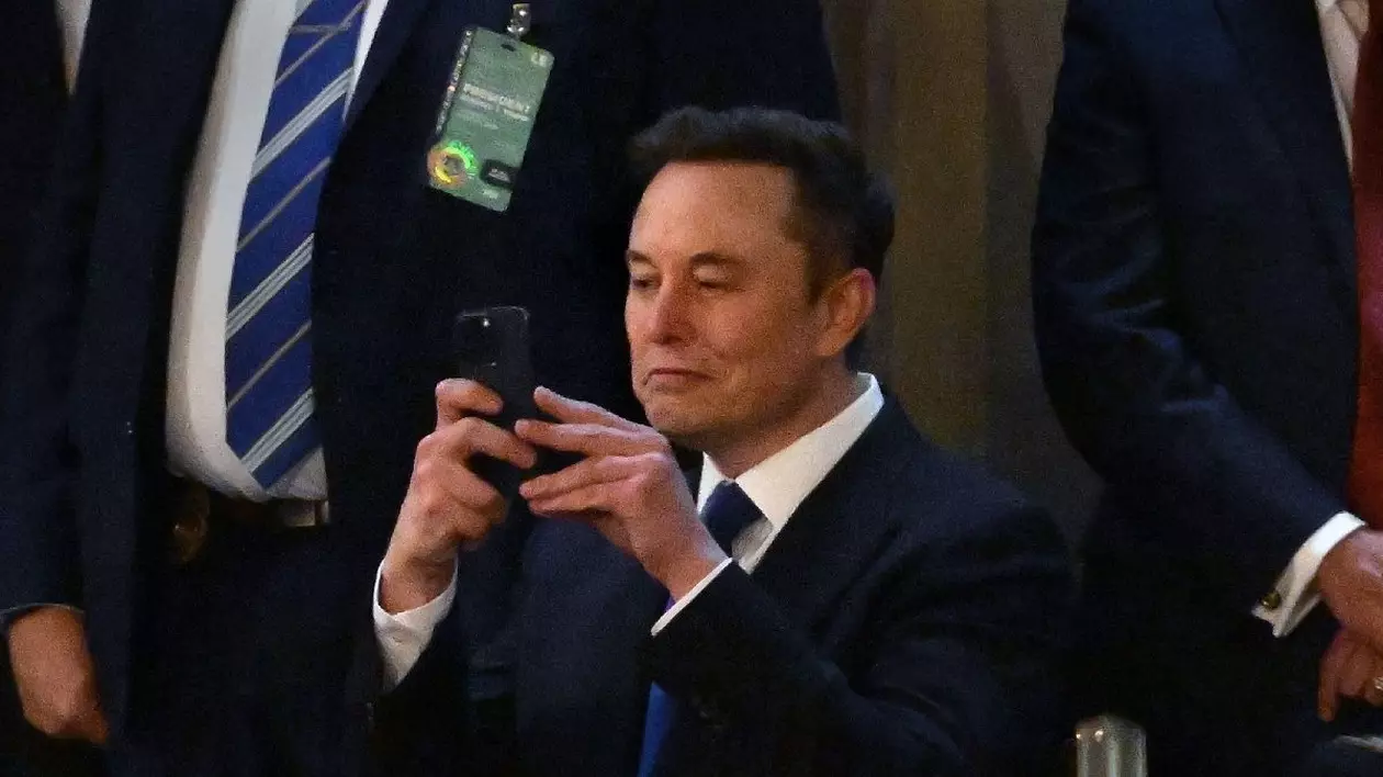 05 martie 2025, SUA, Washington: Elon Musk, care conduce Departamentul pentru Eficiență Guvernamentală (Doge) al președintelui american Donald Trump, își folosește camera telefonului mobil în timp ce președintele Trump vorbește în timpul unui discurs în fața Congresului din Washington.