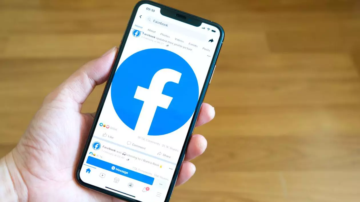 mana unei persoane care tine telefonul deschis cu aplicatia facebook