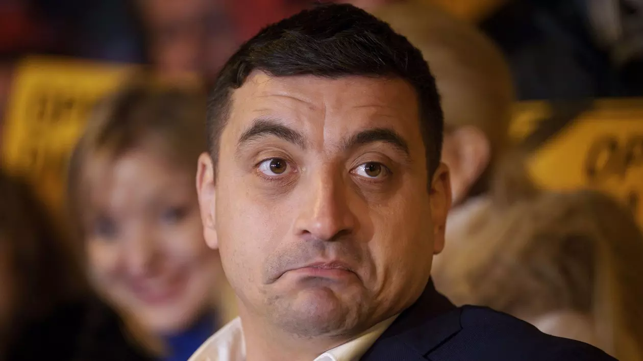 George Simion surprins în cadrul unei conferințe de presă în timp ce se strâmba