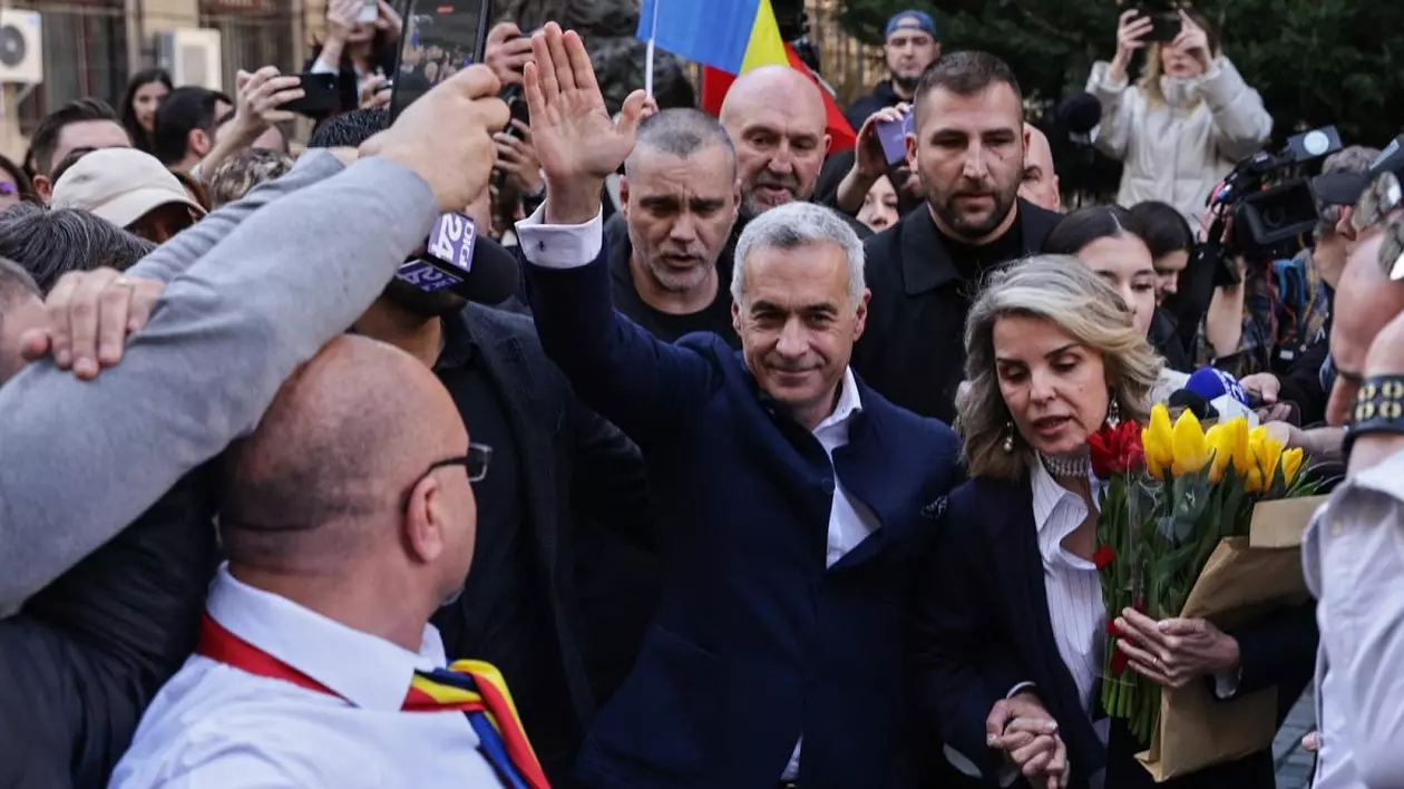 Călin Georgescu, cu brațul drept ridicat în sus, salută mulțimea venită să-l suțină când și-a depus candidatura