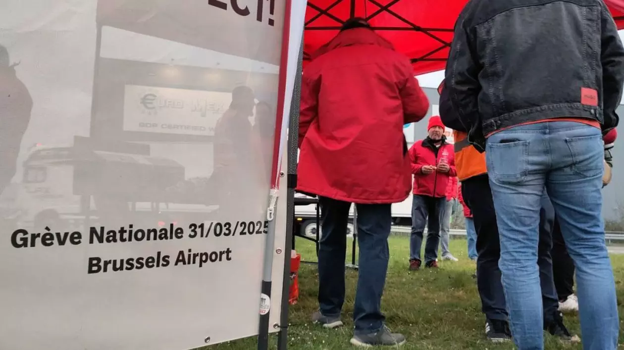 Câțiva oameni s-au adunat la grevă generală, la BRUcargo, zona logistică a Aeroportului Bruxelles, cunoscut ca Zaventem, luni, 31 martie 2025. Oamenii protestează față de reformele de austeritate și pensii ale guvernului federal