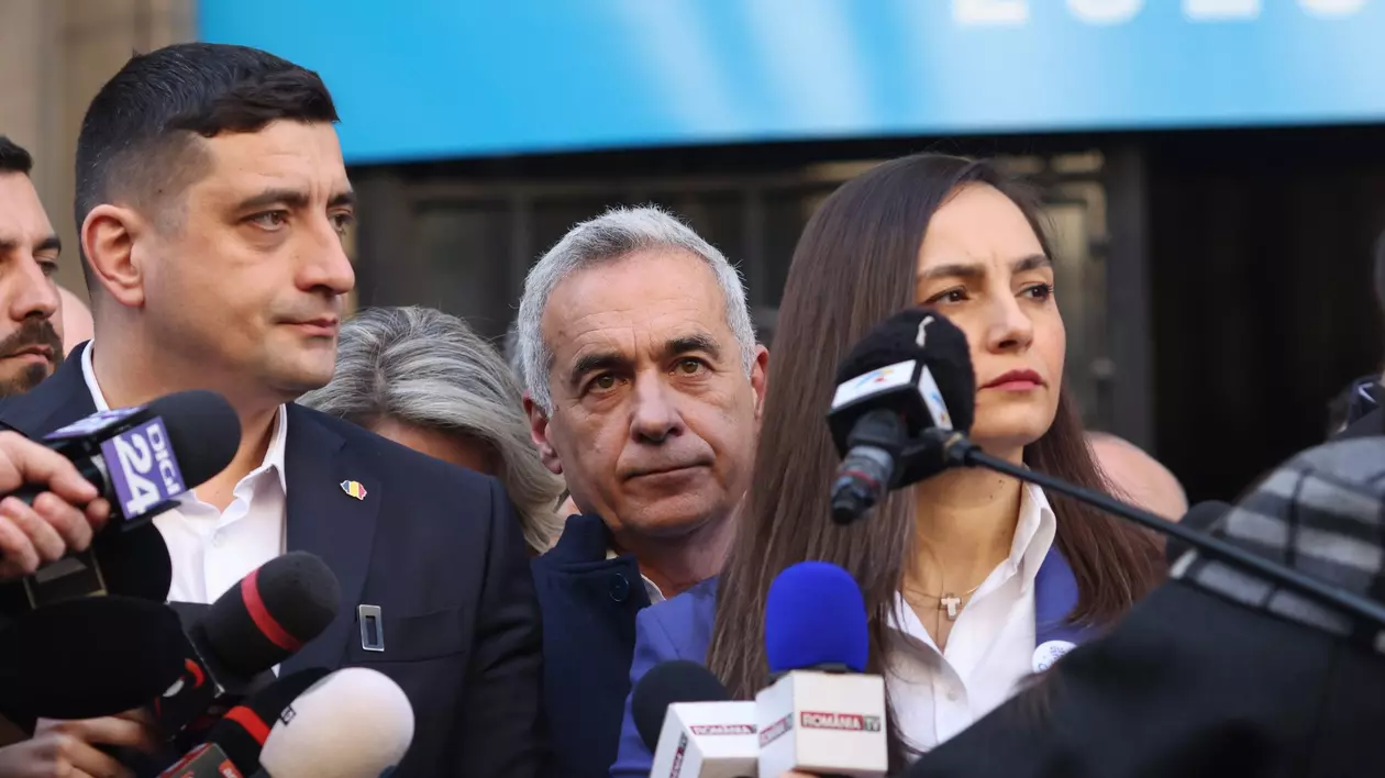 Doi bărbați și o femeie stau în fața mai multor microfoane