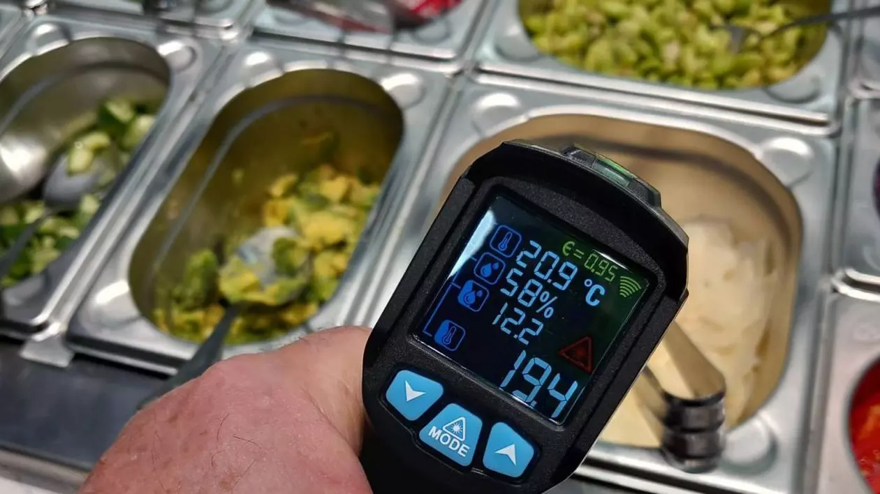 Un bărbat de la ANPC, cu un termometru în mână, măsoară temperatura mâncărurilor dintr-un restaurant, Timișoara, 28 martie 2025