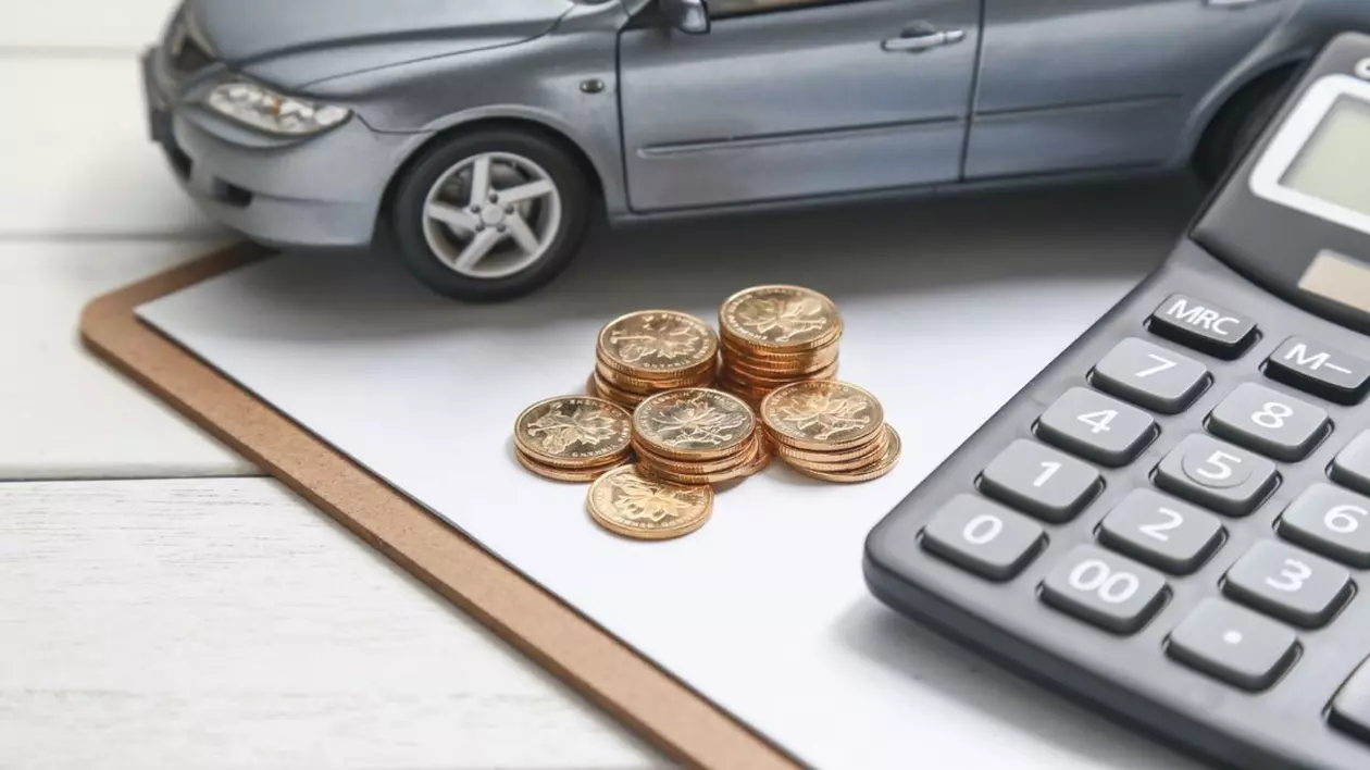 macheta cu mașină, calculator și monede pe masă albă